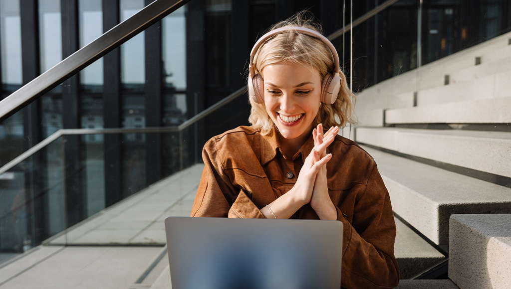 Smiling woman with headphones looking at her laptop